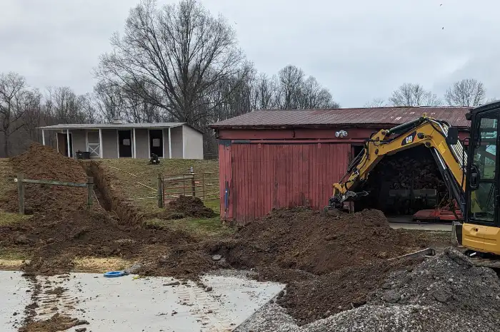 excavator digging a trench for utilities between two buildings