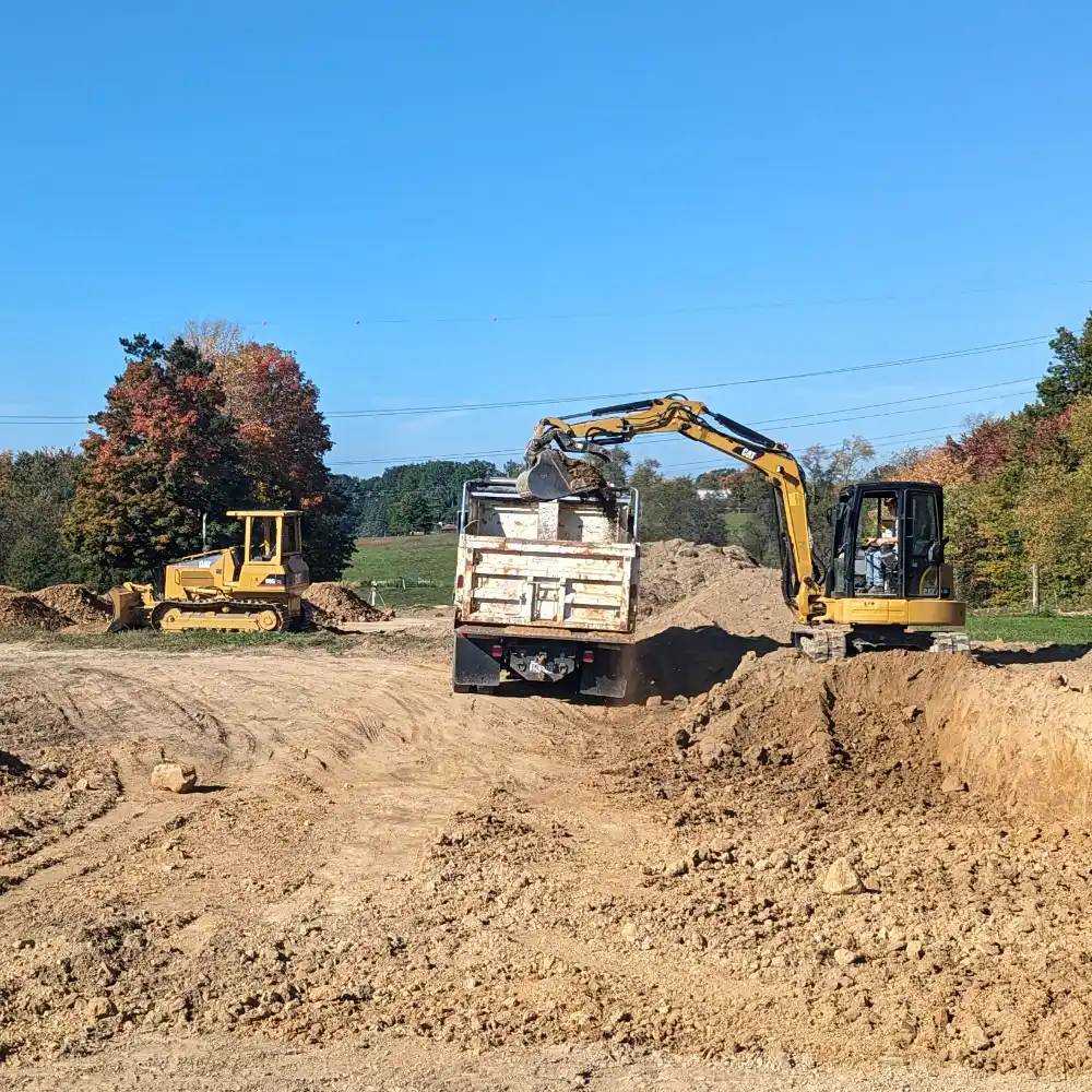 mini excavator loading dirt into dump truck